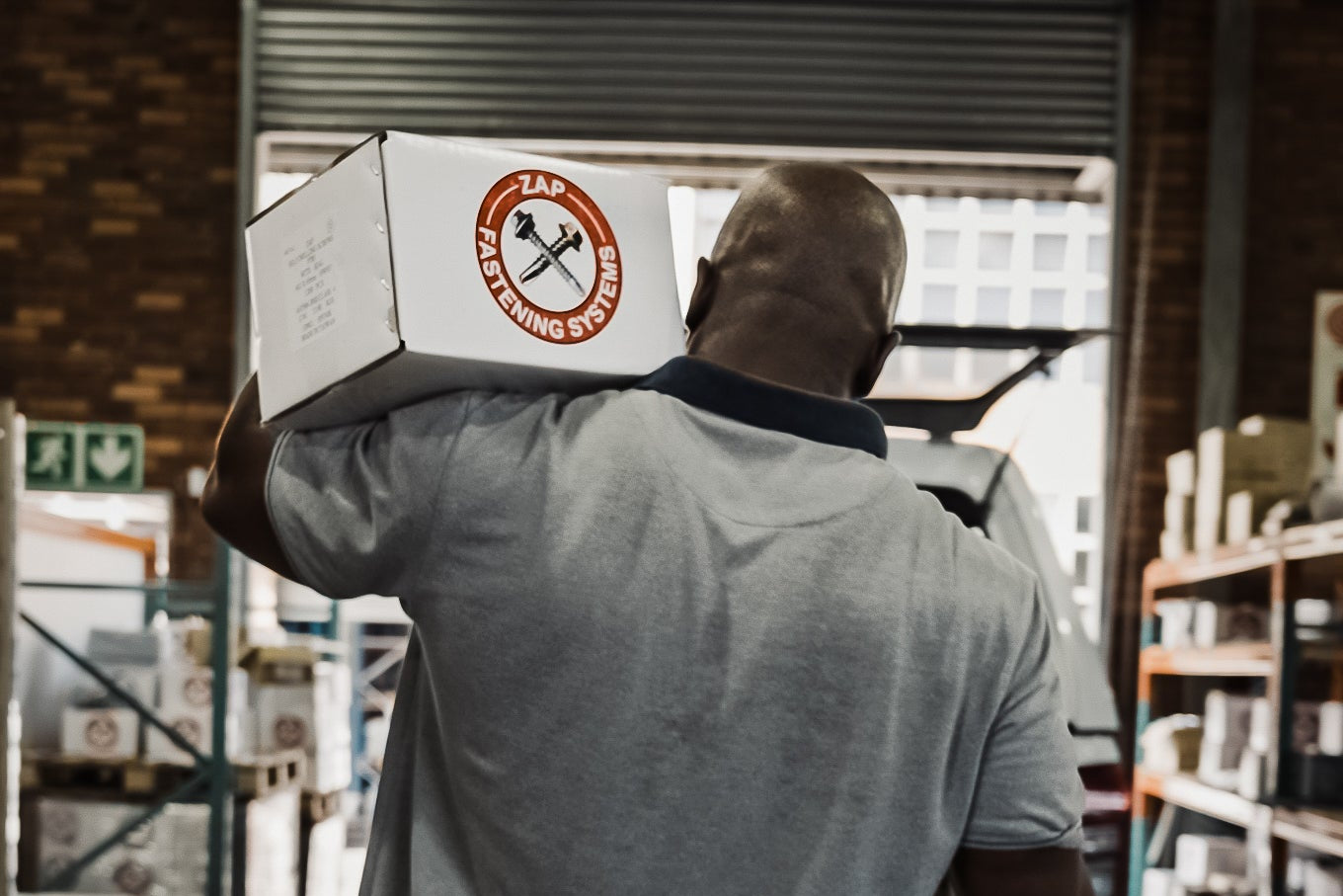 Person carrying a box with a logo in a warehouse setting